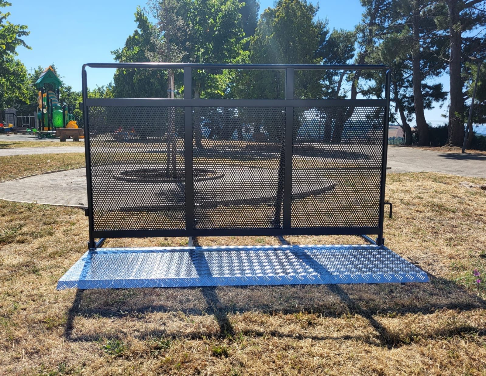Una panchina di metallo in un parco con una recinzione sullo sfondo