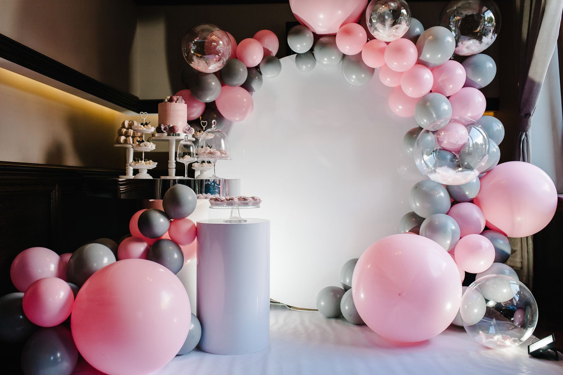Una stanza decorata con palloncini rosa e grigi per un baby shower.